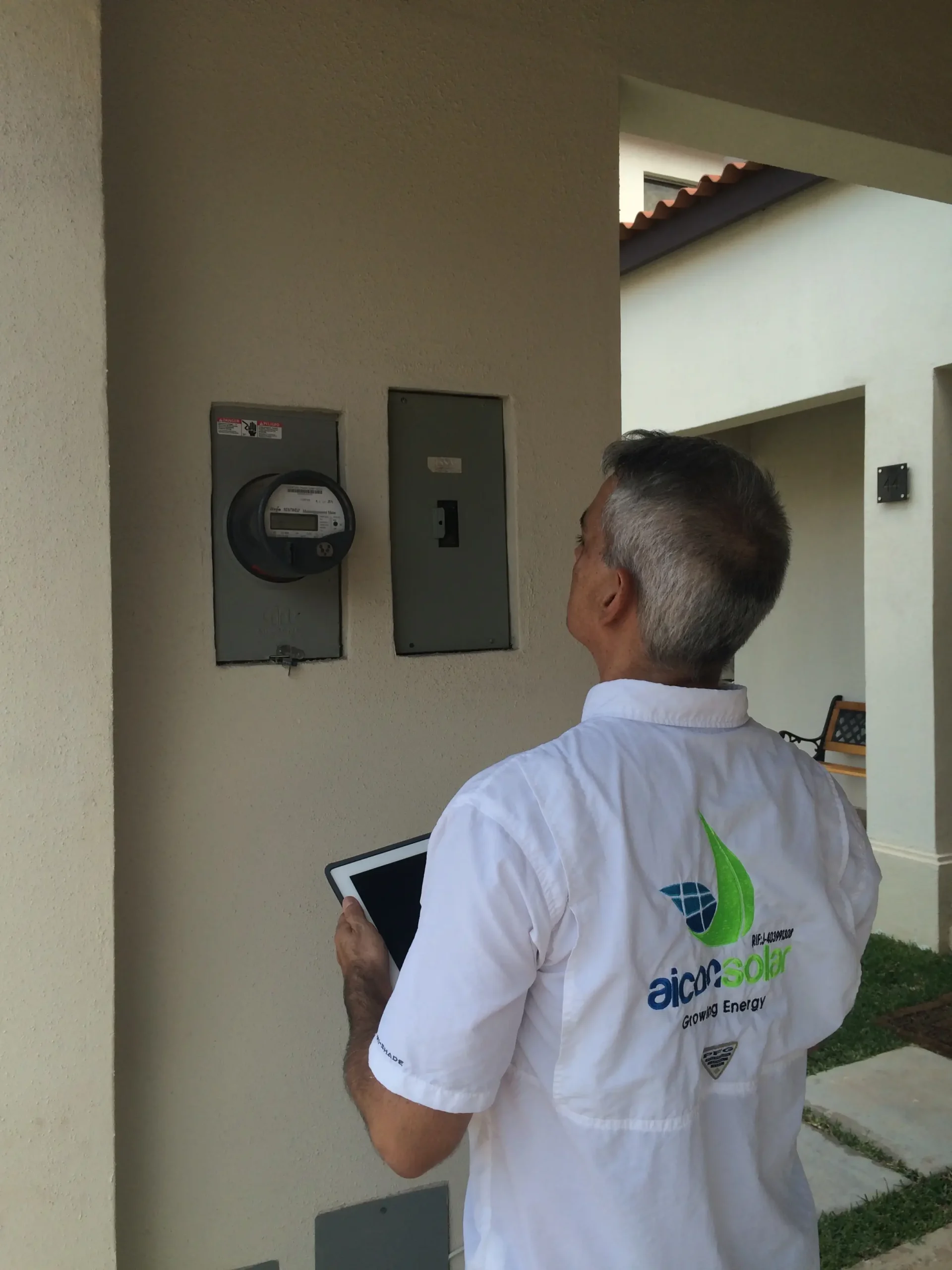 Aicon Solar technician inspecting electric meter with a tablet in hand.