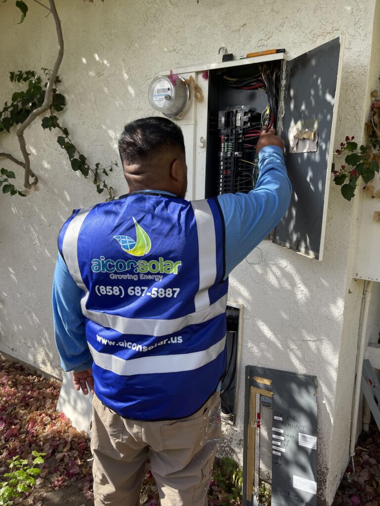 Aicon Solar technician adjusting wires inside an outdoor electrical panel.