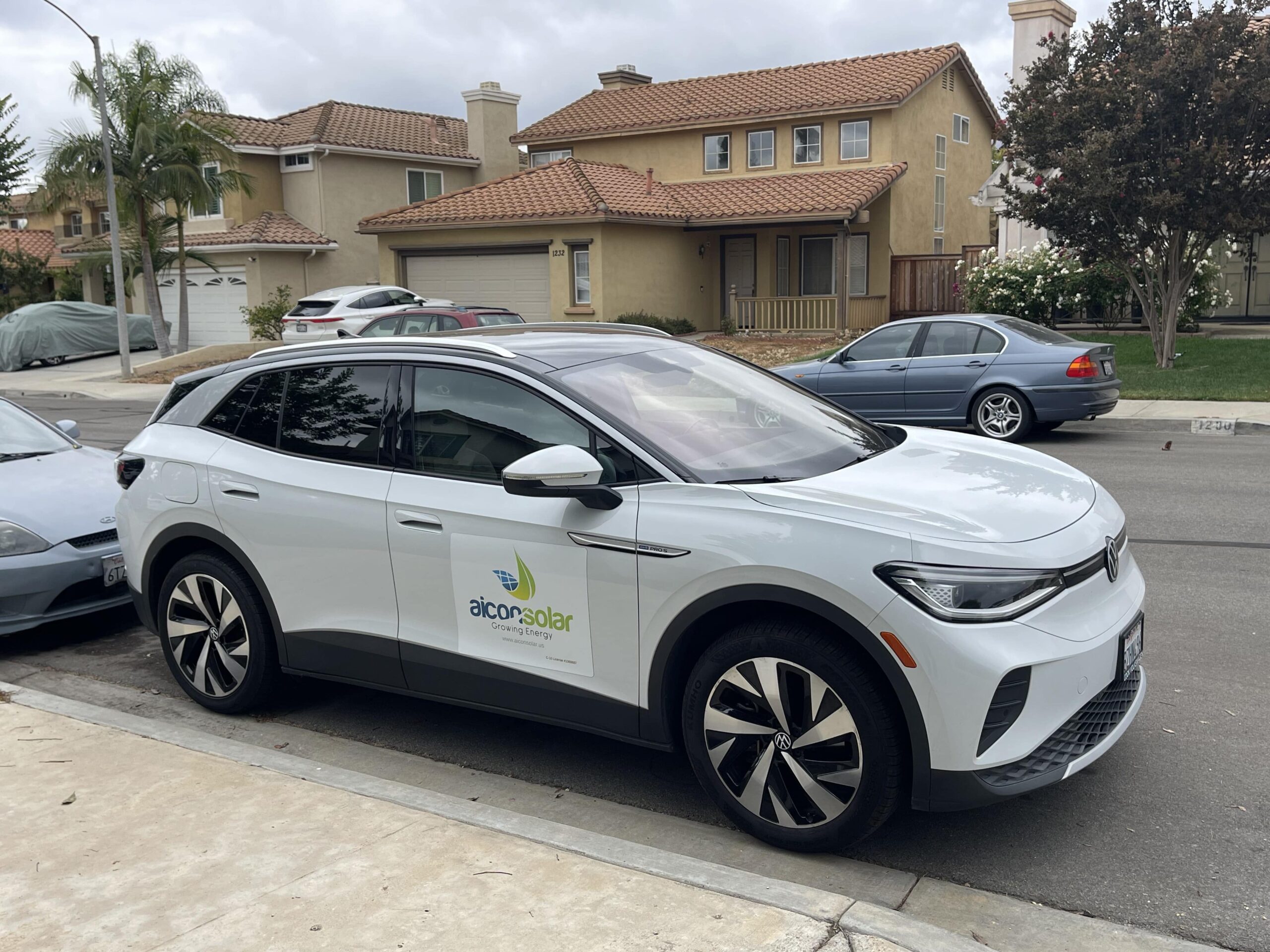 Aicon Solar-branded electric car parked on suburban residential street.