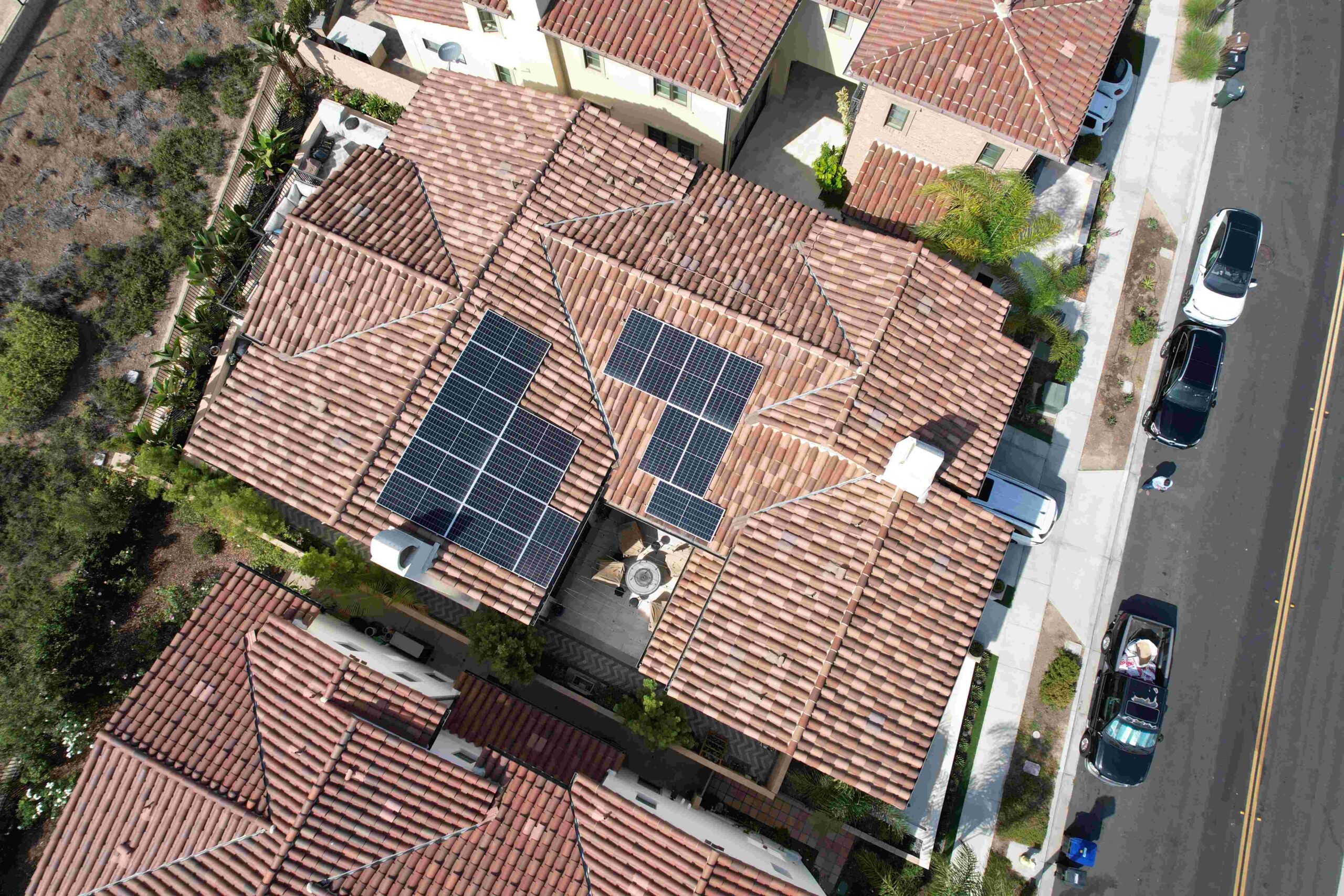 Aerial view of tiled-roof home with solar panels installed in clusters.