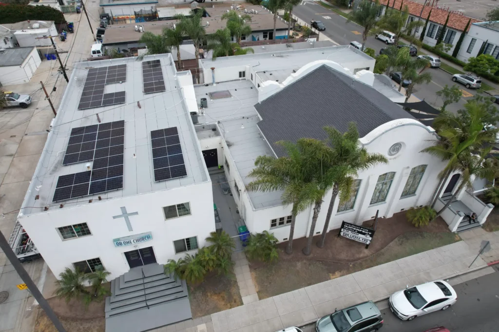 Aerial view of church building with rooftop solar panel installation.