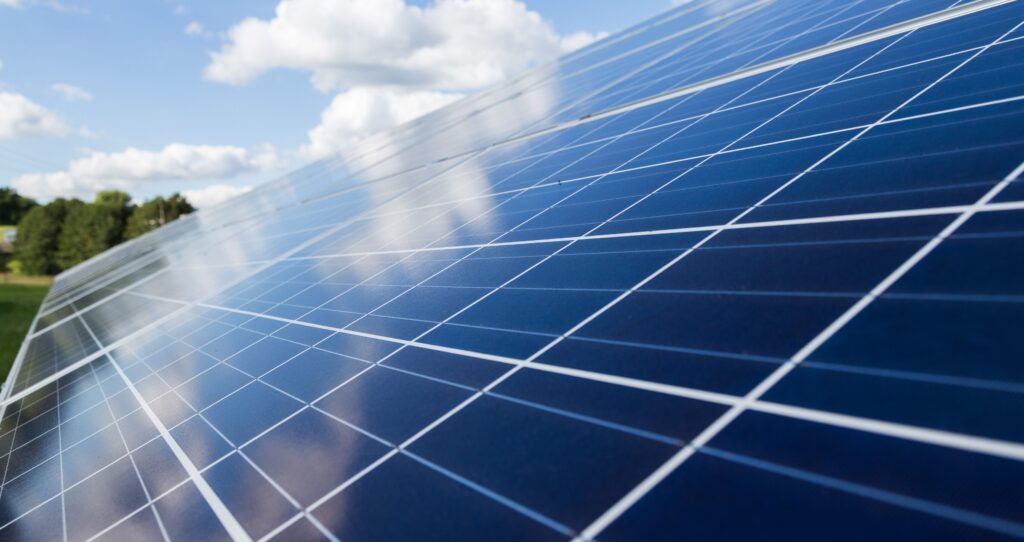 Close-up of solar panel reflecting clouds on a sunny day.