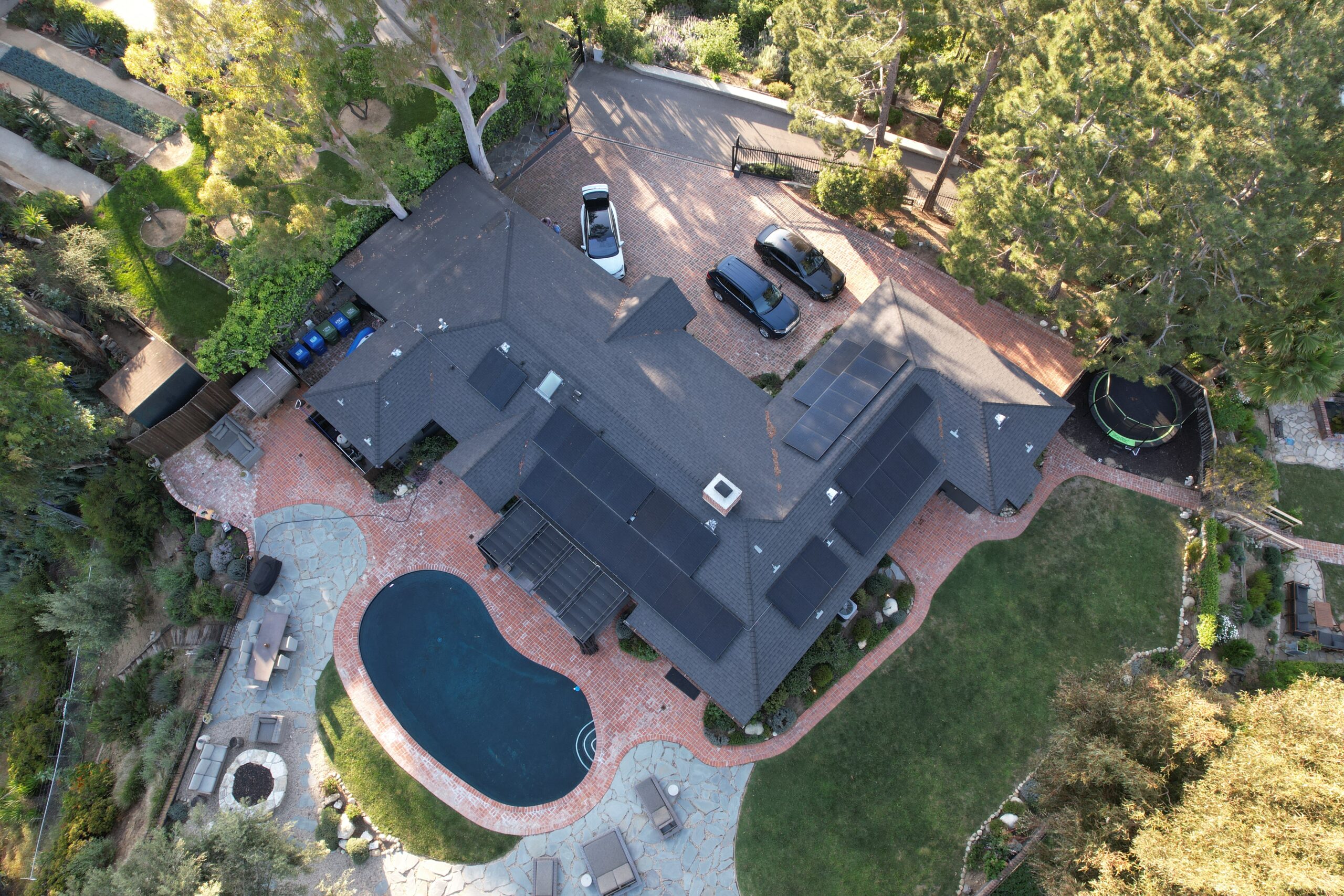 Drone view of residential property with large solar panel array and pool.