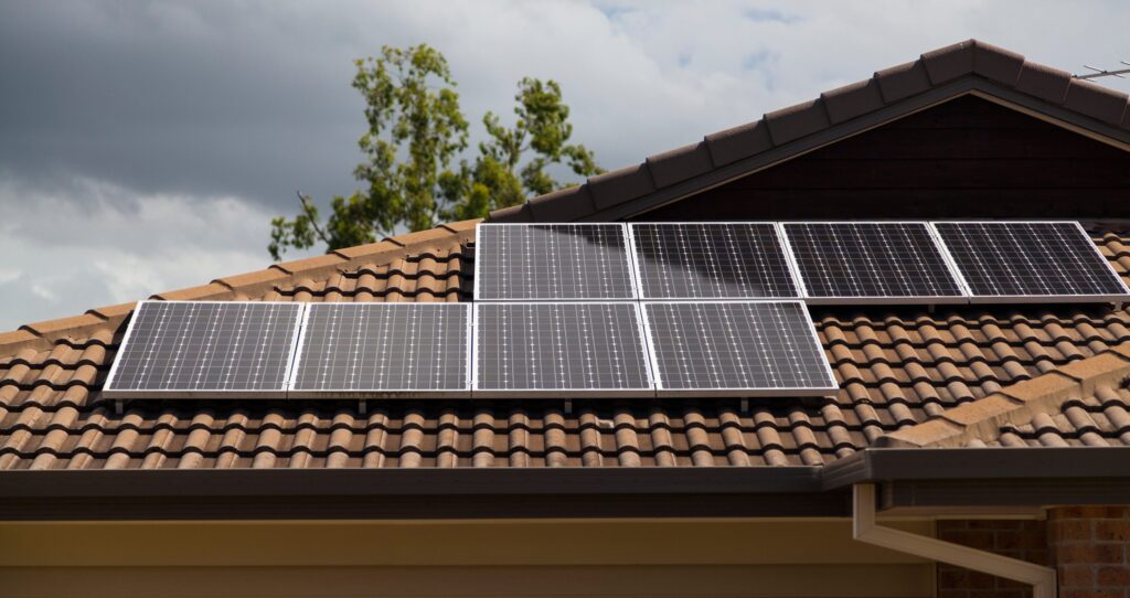 Rooftop with solar panels installed on brown ceramic tiles.