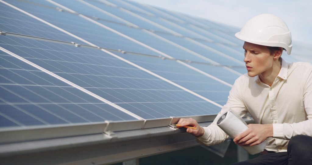Engineer in white helmet inspecting rooftop solar panel installation.