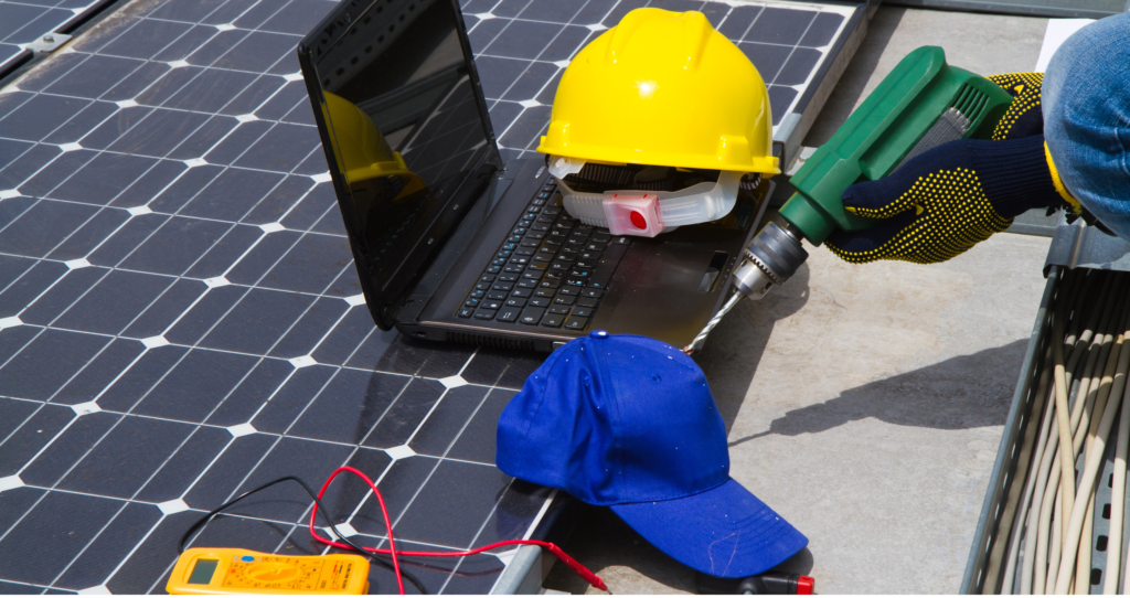 Tools, helmet, and laptop on solar panel during maintenance work.