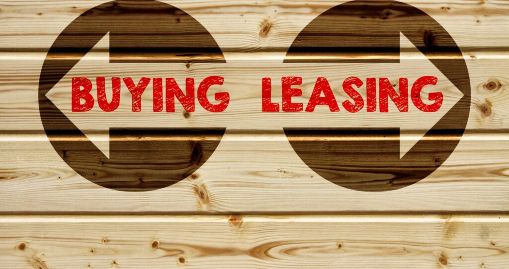Wooden board with arrows labeled “BUYING” and “LEASING” in red.