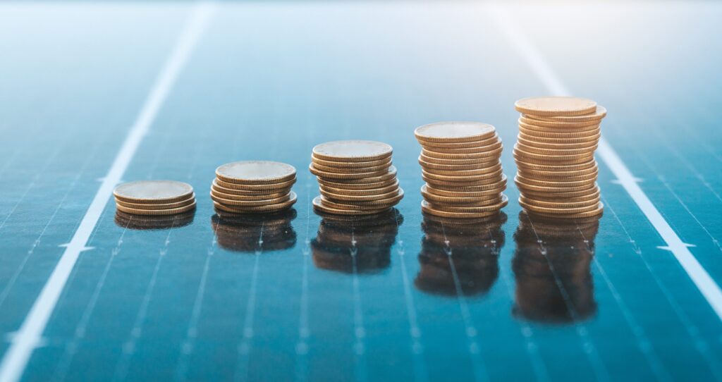Increasing stacks of coins placed on solar panel surface.